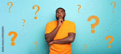 Confuse and pensive expression of a boy with many questions . cyan colored background