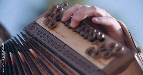 Close up slow motion shot, musician in traditional music costume playing wooden accordion, 4K.