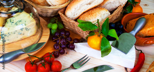 Buffet food -  bread in baskets, wine, fruit, chilli and cheeses - food concept as a panorama / banner / header. photo