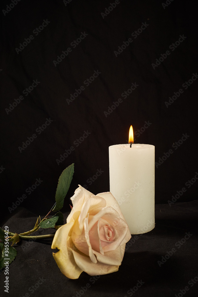 Burning candle and a beautiful rose on a black background Burning candle and a beautiful rose on a black background