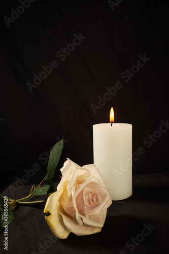 Burning  candle and a beautiful rose on a black background