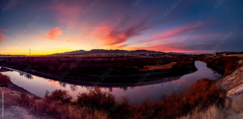 Panoramic sunset over the mountains with the sky reflecting on the surface of the river