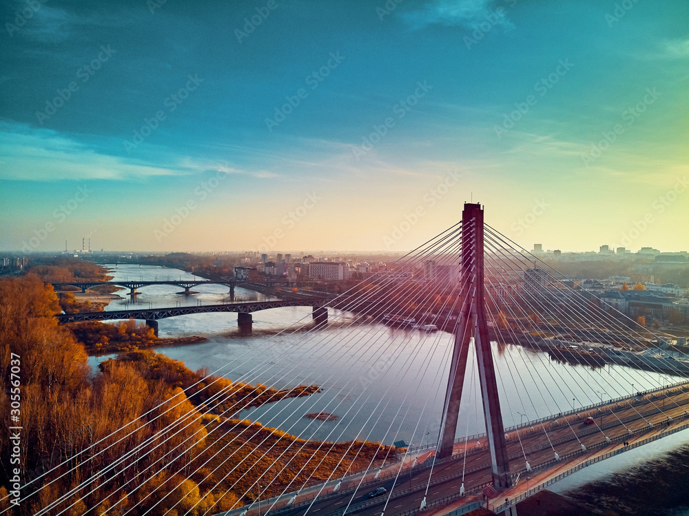 Obraz premium Beautiful panoramic aerial dsrone view to Swietokrzyski Bridge (Polish: Swietokrzyski) and The PGE Narodowy or National Stadium - football stadium located in Warsaw, Poland in autumn evening at sunset