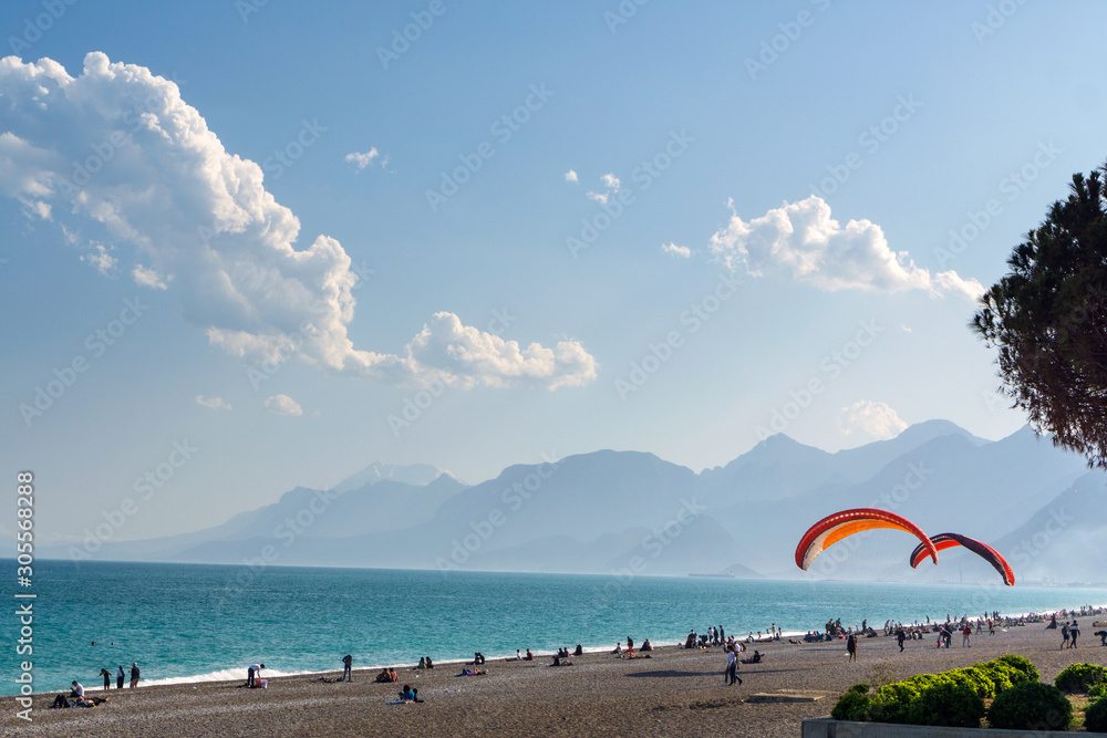 Beach on the beach with paragliders on the background of mountains