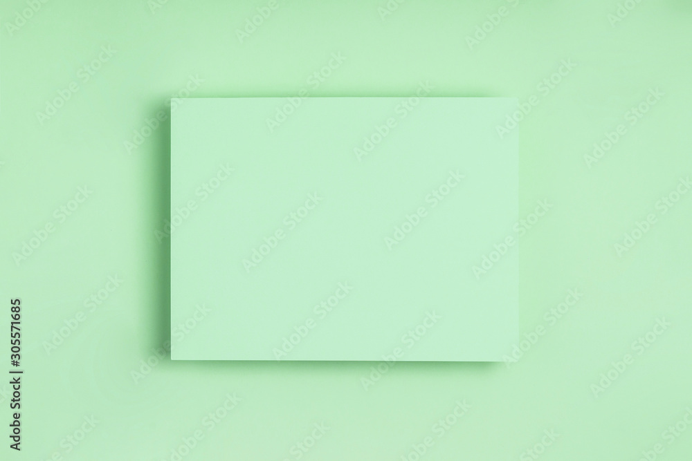 Minimal frame geometric composition mock up. Blank sheet of delicate green paper on green background. Template design invitation card. Top view, flat lay, copy space. Horizontal orientation.