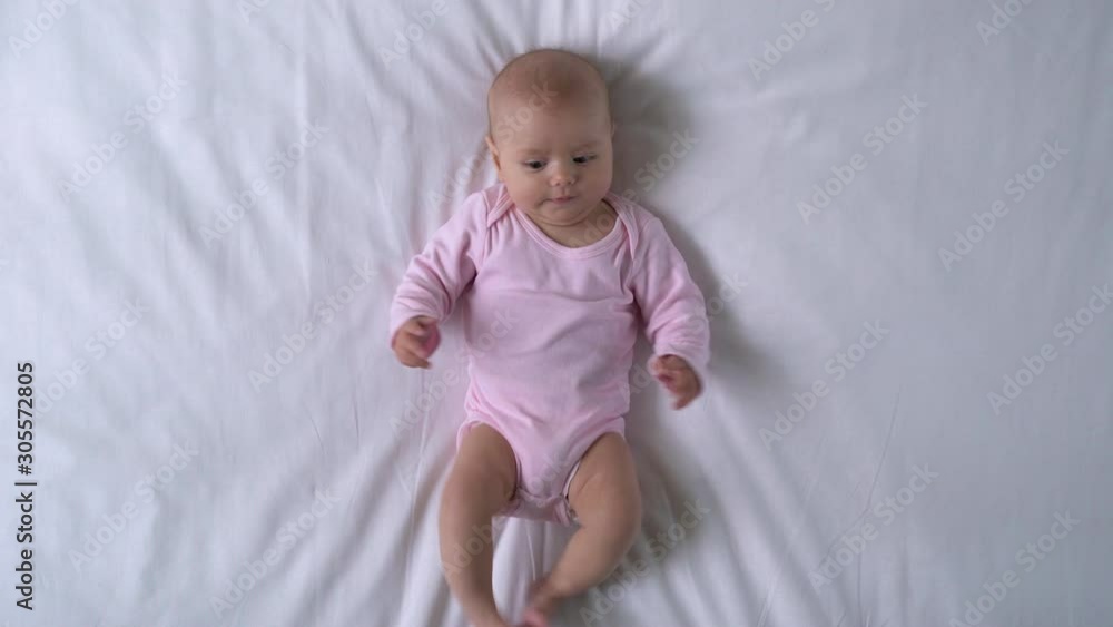 Charming baby playing legs and arms, chewing sweet tiny fingers, happy infancy Charming baby playing legs and arms, chewing sweet tiny fingers, happy infancy