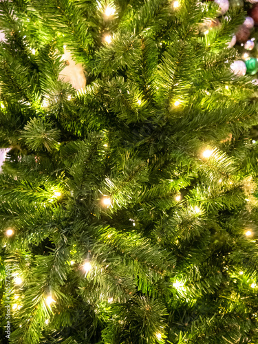 Green Christmass tree fir texture with lights and balls background.