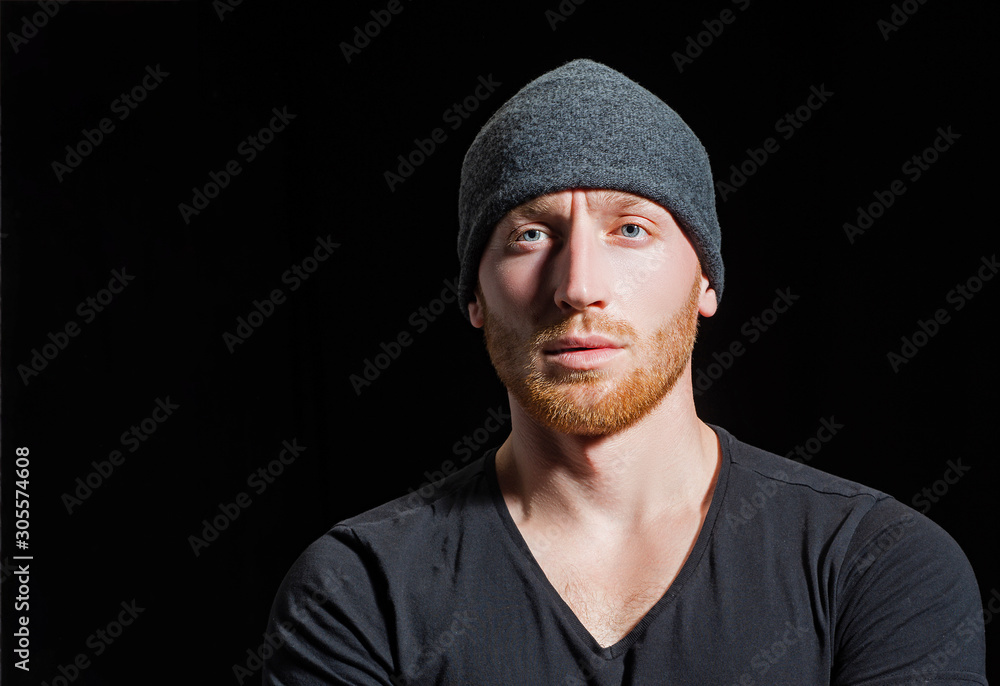 Young handsome hipster in hat. Barbershop advertising. Portrait of sporty handsome masculine virile attractive proud concentrated confident muscular man. Copy space. In casual dark t shirt. Young handsome hipster in hat. Barbershop advertising. Portrait of sporty handsome masculine virile attractive proud concentrated confident muscular man. Copy space. In casual dark t shirt.