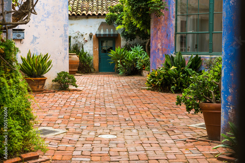 Fototapeta Naklejka Na Ścianę i Meble -  Picturesque garden courtyard with potted plants and enclosed by rustic plaster walls in vibrant hues of purple, pink, and blue