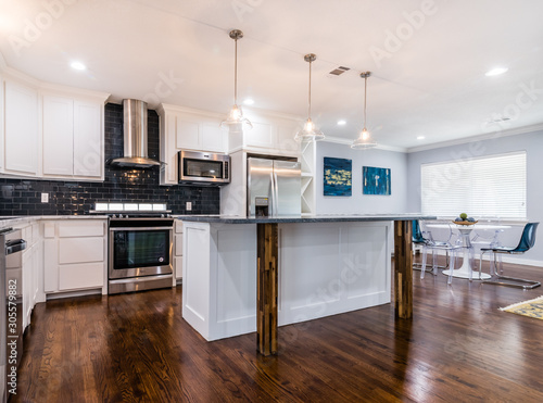 Open concept Kitchen and dining area,  blue accents, wood flooring, custom island, natural light