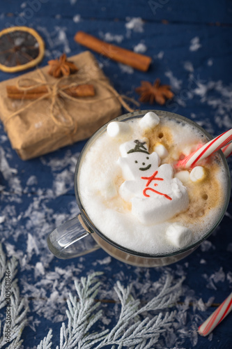 Christmas and New Year. Marshmallow snowman in hot latte in a mug. Vertical photo.