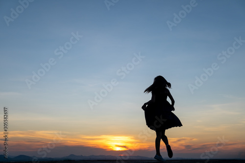 Silhouette of free woman enjoying freedom feeling happy at sunset,dancing
