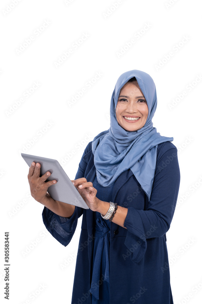 Old veiled woman with a smile holding a digital tablet looking at the camera with an isolated background Old veiled woman with a smile holding a digital tablet looking at the camera with an isolated background