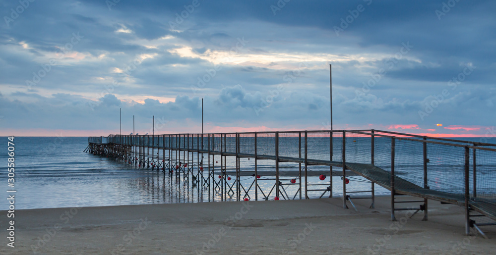 dock at rivazzurra beach (Rimini/Italy) in the morning light; dramatic ocean sunrise landscape