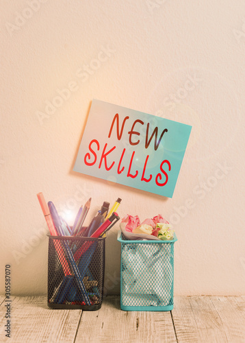 Text sign showing New Skills. Business photo text Recently Acquired Learned Abilities Knowledge Competences Blue Sticky Card on Wall Two Pencil Pots Pens Pencils Markers Waste Paper