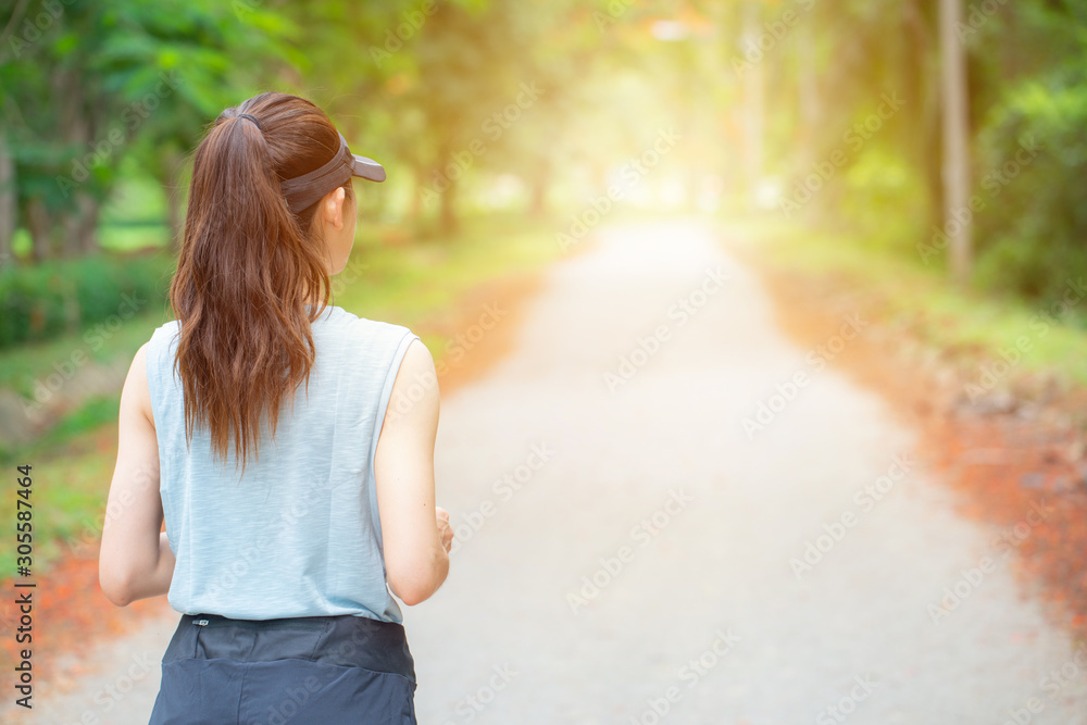 Back view of young runner woman running on the way in the park. Running is a great way to help improve cardiovascular health, burns calories and can build strength. Back view of young runner woman running on the way in the park. Running is a great way to help improve cardiovascular health, burns calories and can build strength.