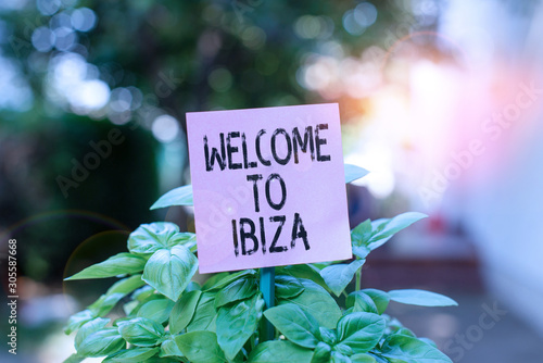 Text sign showing Welcome To Ibiza. Business photo showcasing Warm greetings from one of Balearic Islands of Spain Plain empty paper attached to a stick and placed in the green leafy plants © Artur