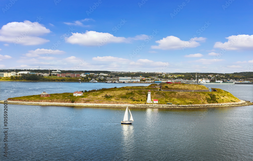 Panoramic view of Halifax Harbor with lighthouse on island and sail boat on sunny day