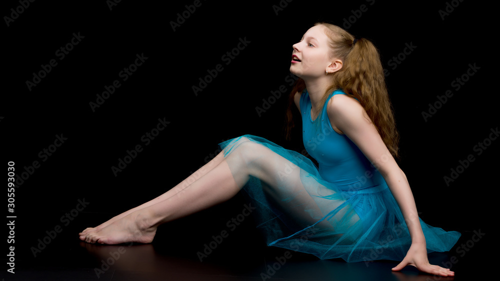 Girl gymnast in the studio on a black background performs gymnas Girl gymnast in the studio on a black background performs gymnas