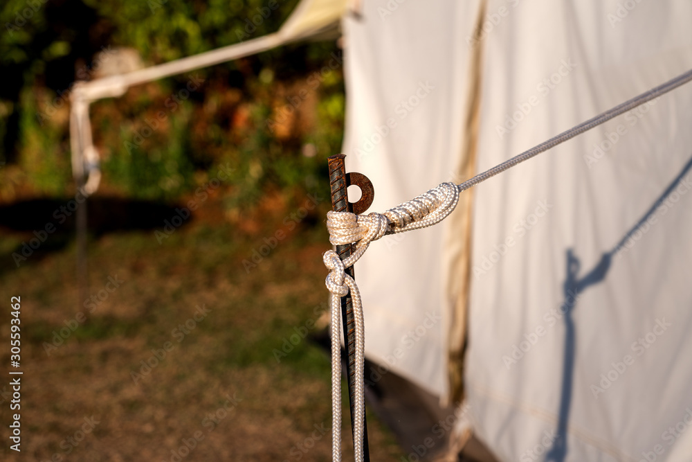 Close up at rope knot with anchor rod which is a part of camping tent structure. Gear/equipment Camping and recreation activity.