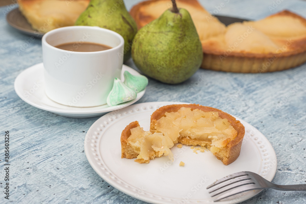 Delicious home bake poached pear tart pie, as known as Tarte Bourdaloue, a cup of coffee latte. French popular recipe that gets the name from a street in Paris. Food on table concept. Delicious home bake poached pear tart pie, as known as Tarte Bourdaloue, a cup of coffee latte. French popular recipe that gets the name from a street in Paris. Food on table concept.
