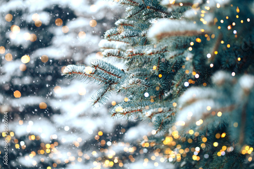 Christmas tree outdoor with snow, lights bokeh around, and snow falling, Christmas atmosphere.