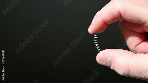 finger and thumb compressing a metal spring