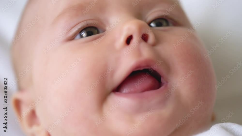Cheerful newborn baby smiling and babbling, curiously looking around, childhood Cheerful newborn baby smiling and babbling, curiously looking around, childhood