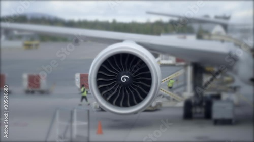 Close Up of Airplane Jet Turbine Spinning While Plane is Parked at Terminal With Workers photo