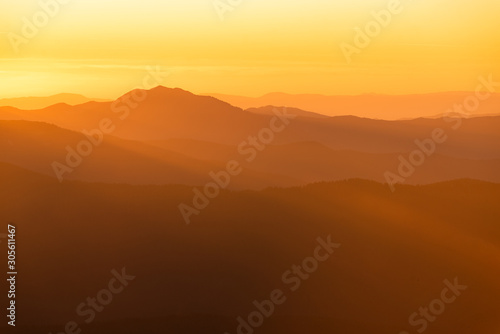 Mountain range with visible silhouettes through the morning colorful fog. © dvv1989