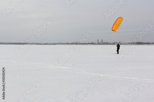 Kiteboarder with orange kite on the snow, Ob reservoir, Novosibirsk, Russia