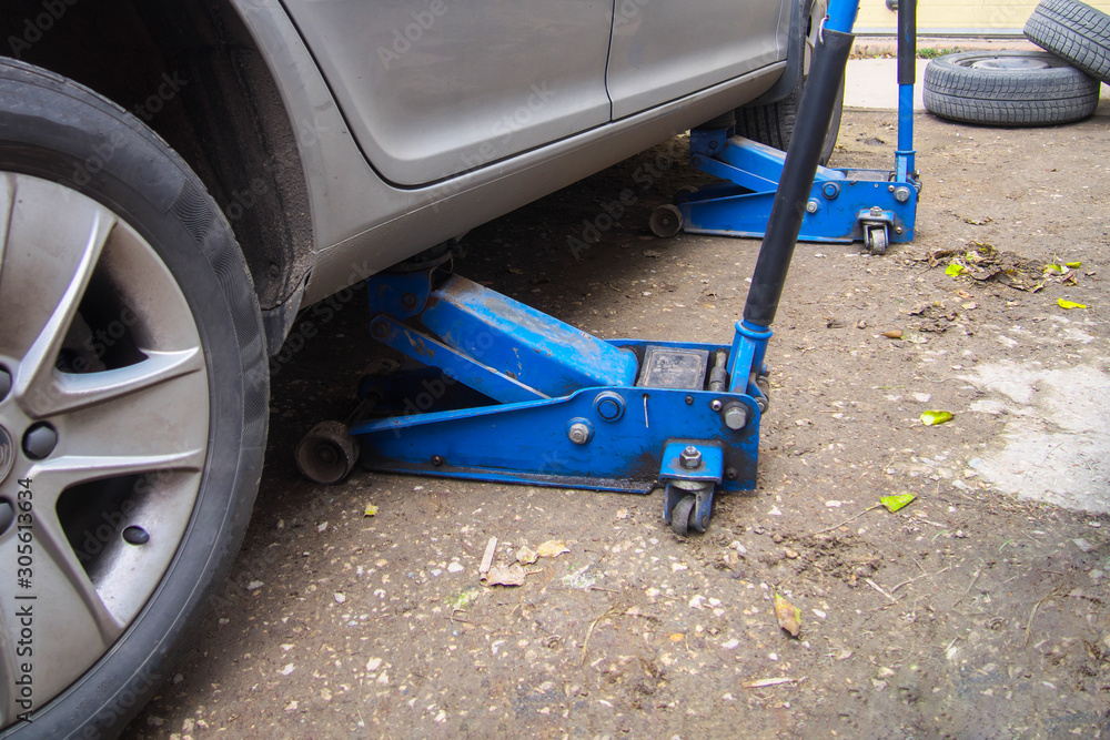 Fototapeta premium blue jack, replacing wheels on a car