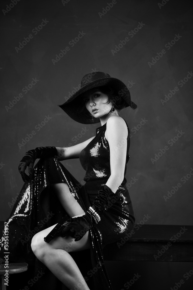 girl in a blue evening dress and in a black hat on a gray background girl in a blue evening dress and in a black hat on a gray background