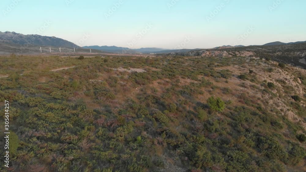 Drone fly over a white young caucasian man standing over a cliff and reveal a stunning wild landscape with river and canyon. Wind turbines on the background, fresh clean air renewable energy concept Drone fly over a white young caucasian man standing over a cliff and reveal a stunning wild landscape with river and canyon. Wind turbines on the background, fresh clean air renewable energy concept