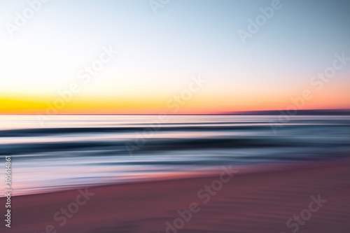 Abstract seascape. Sunrise over the sea. Motion blur, play of ripples. Pink, yellow, purple, and blue colors