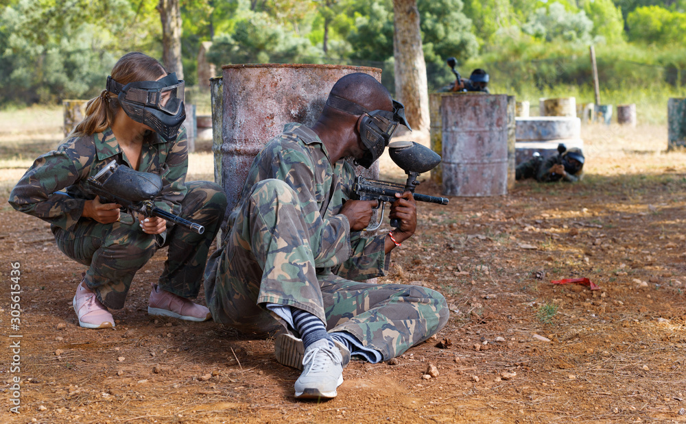 Fototapeta premium Two opposing teams shooting on paintball playing field outdoors