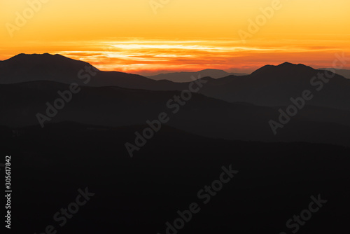 Orange and yellow sunset with mountains silhouettes. Gradient vivid nature background. © dvv1989