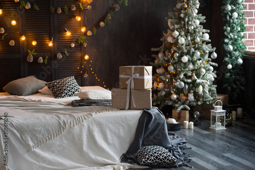 Christmas tree with white and black gifts in the bedroom Christmas. Beautifully decorated house with a silver, white and black tree and presents at Christmas. Magic time.
