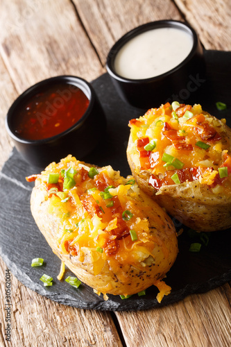 Baked potatoes with cheddar cheese, green onions and bacon close-up. vertical