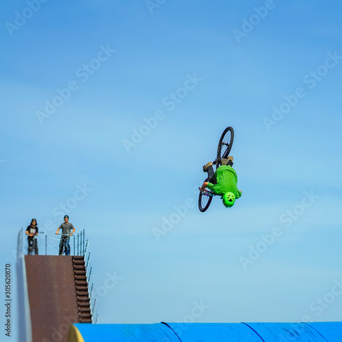 Aerial BMX stunt. Young unrecognizable bike rider performing air trick back flip. Extreme sport, youth culture and leisure