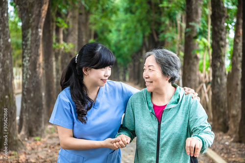 Smiling nurse helping senior woman to walk around the park © Tom Wang