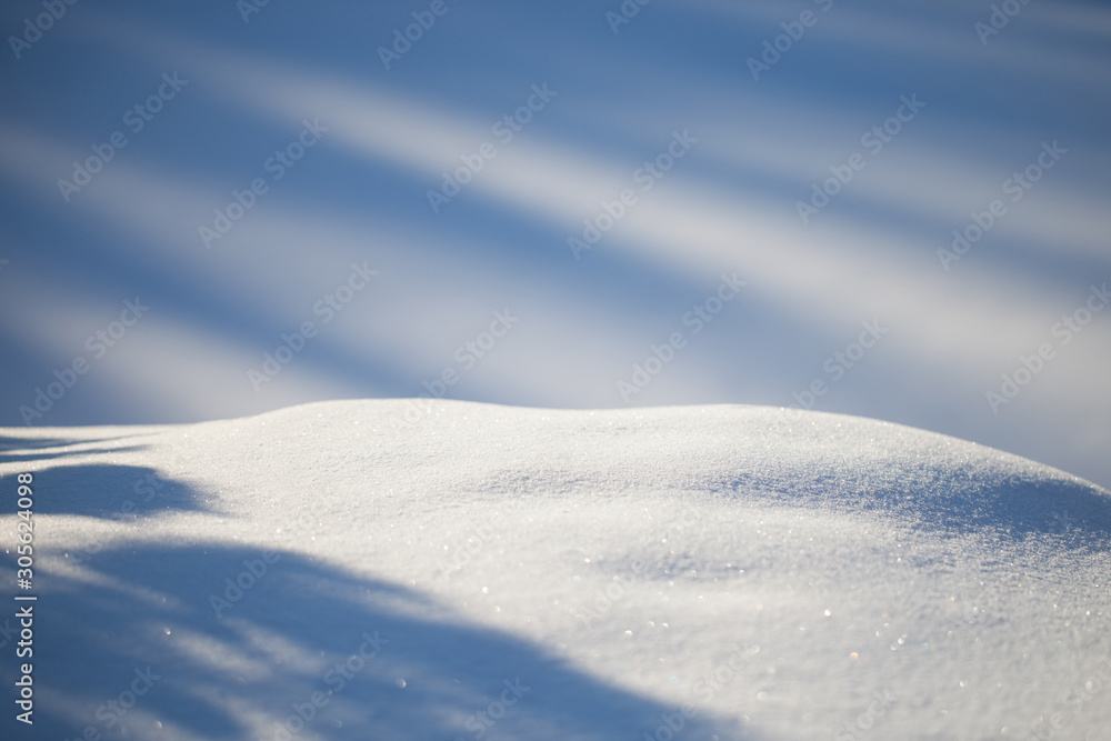 Background of a snowy landscape against a blurred fond. Fresh snow texture in blue tone. Copy space for text.