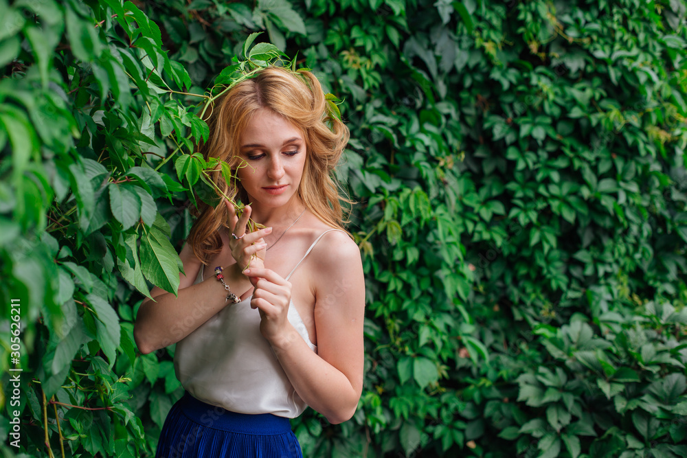 Portrait of a young beautiful woman, standing next to the wall of wild grape leaves. Portrait of a young beautiful woman, standing next to the wall of wild grape leaves.