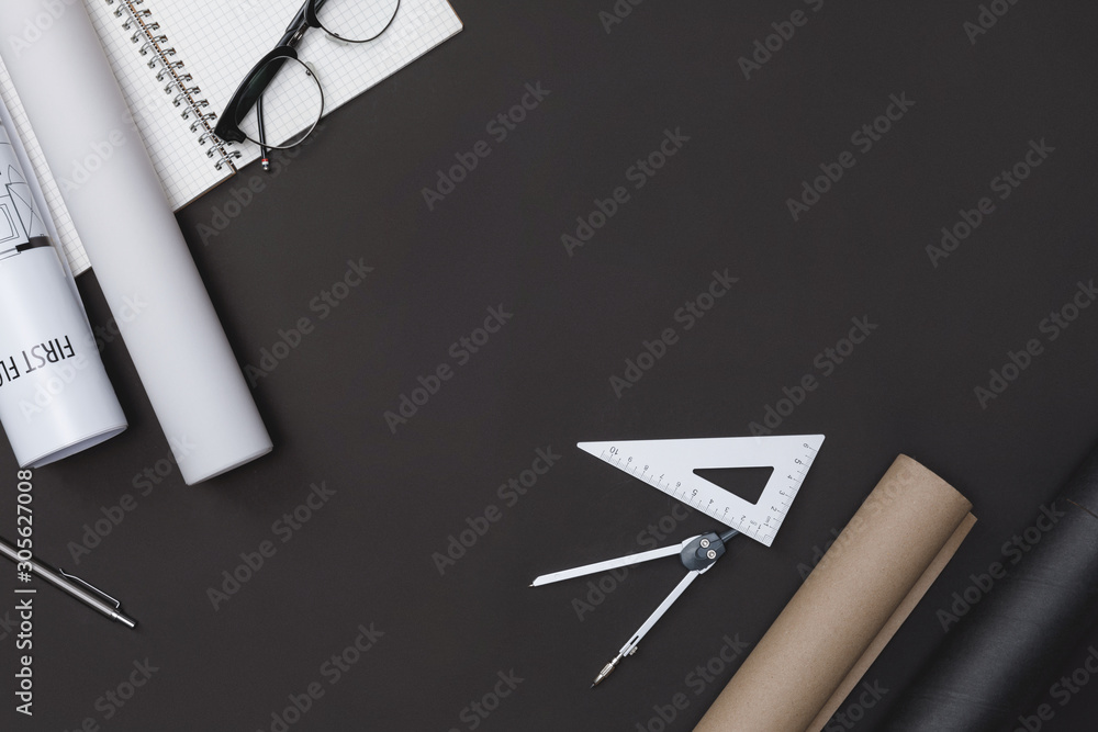 Creative flat lay of architects black table with roll blueprints, architectural project plan, engineering tools and office supplies, Workspace for new designer concept, Top view with copy space Creative flat lay of architects black table with roll blueprints, architectural project plan, engineering tools and office supplies, Workspace for new designer concept, Top view with copy space