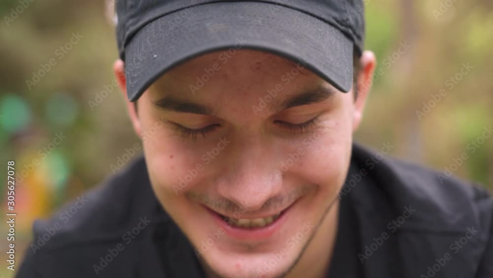 Insidious boy in a cap with green sly eyes, mustache and broad cunning smile blinking and looking into the camera on the street, close-up Insidious boy in a cap with green sly eyes, mustache and broad cunning smile blinking and looking into the camera on the street, close-up