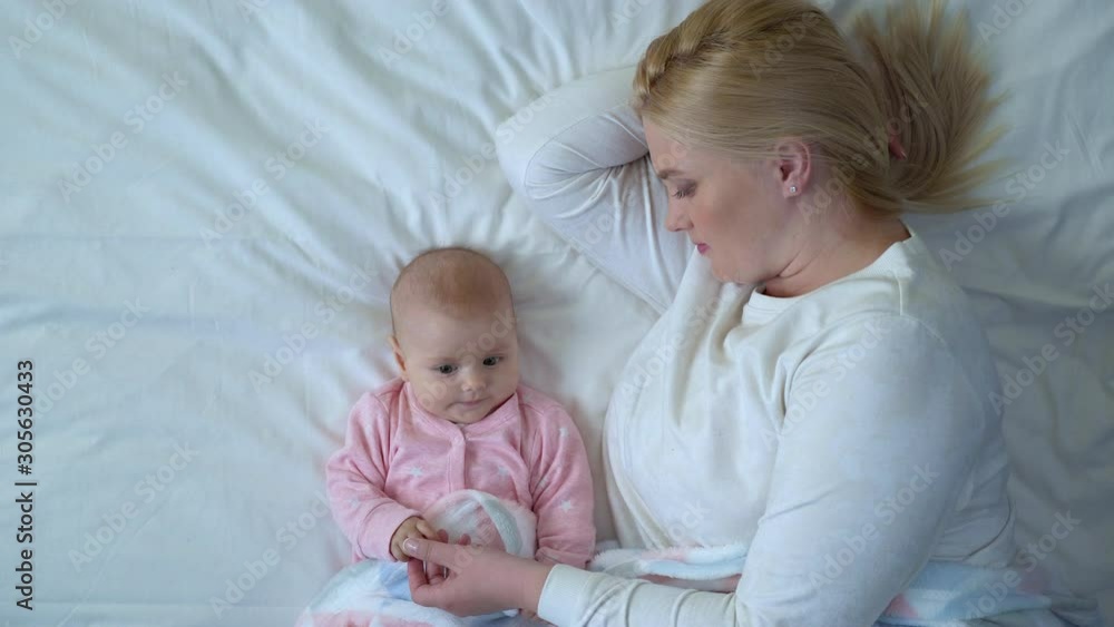 Young mother looking at baby with love, gently touching infant hands, family Young mother looking at baby with love, gently touching infant hands, family