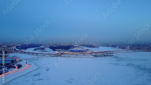 Krestovsky Island aerial panoramic view from Neva Bay side, winter season frozen Gulf of Finland water covered with ice and snow. Evening twilight, Zenit Arena stadium and Western Rapid Diameter road photo