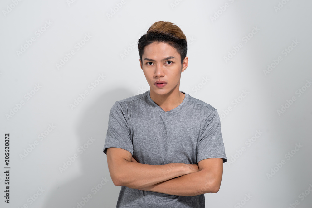 Young Asian male is looking to the camera crossed his hands over white background. Young Asian male is looking to the camera crossed his hands over white background.
