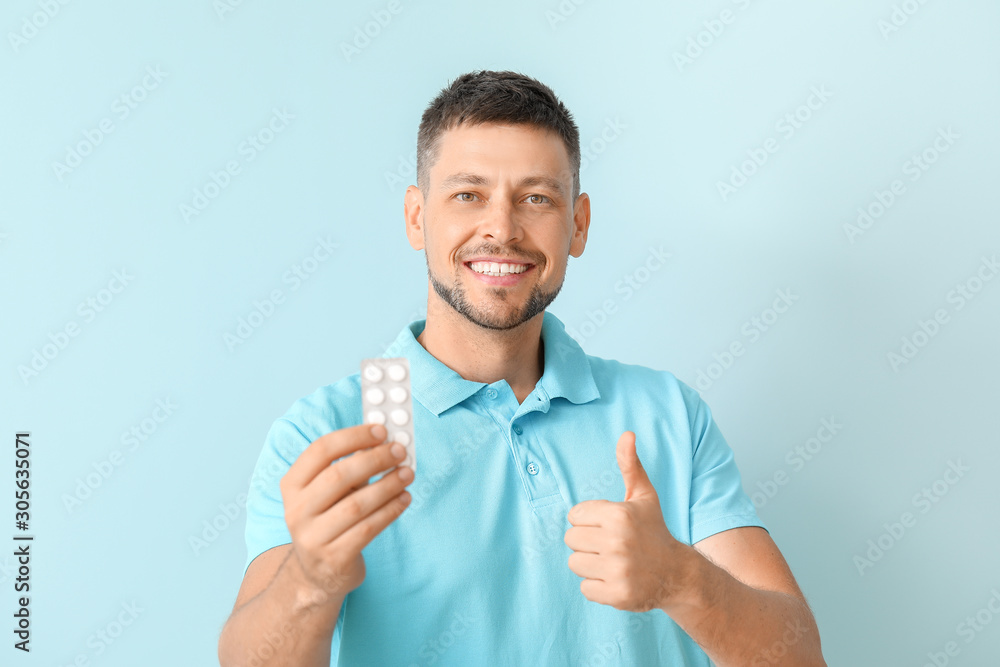 Man with pills showing thumb-up on color background Man with pills showing thumb-up on color background