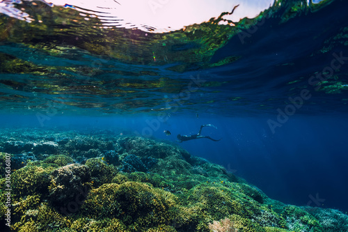 Free diver dive in deep ocean, underwater view with rocks and corals. Freediving